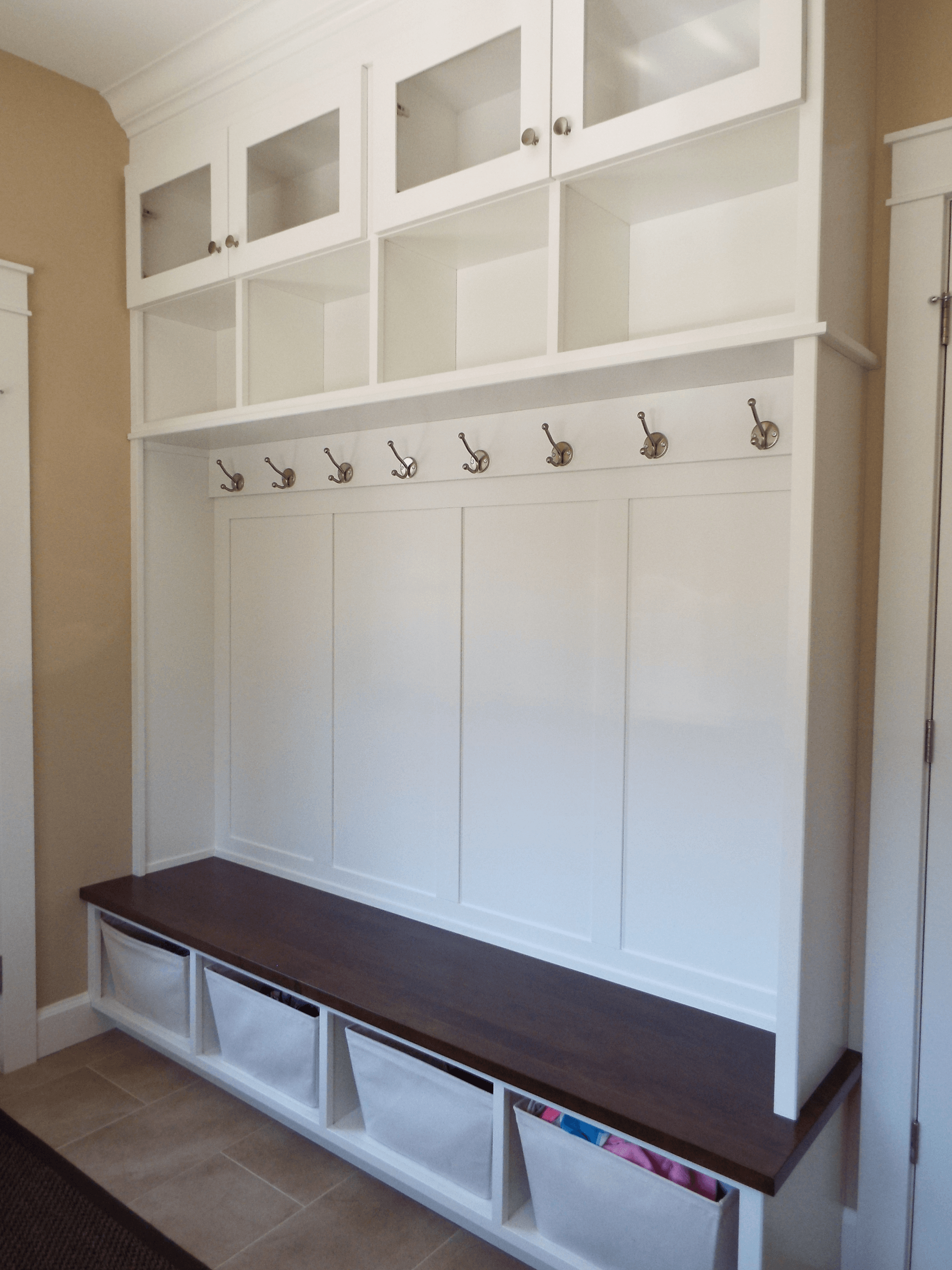 A hallway with a bench and hooks on the wall