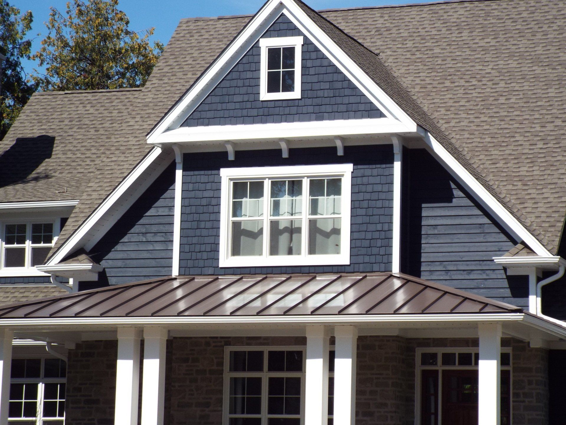 A blue house with a brown roof and white trim