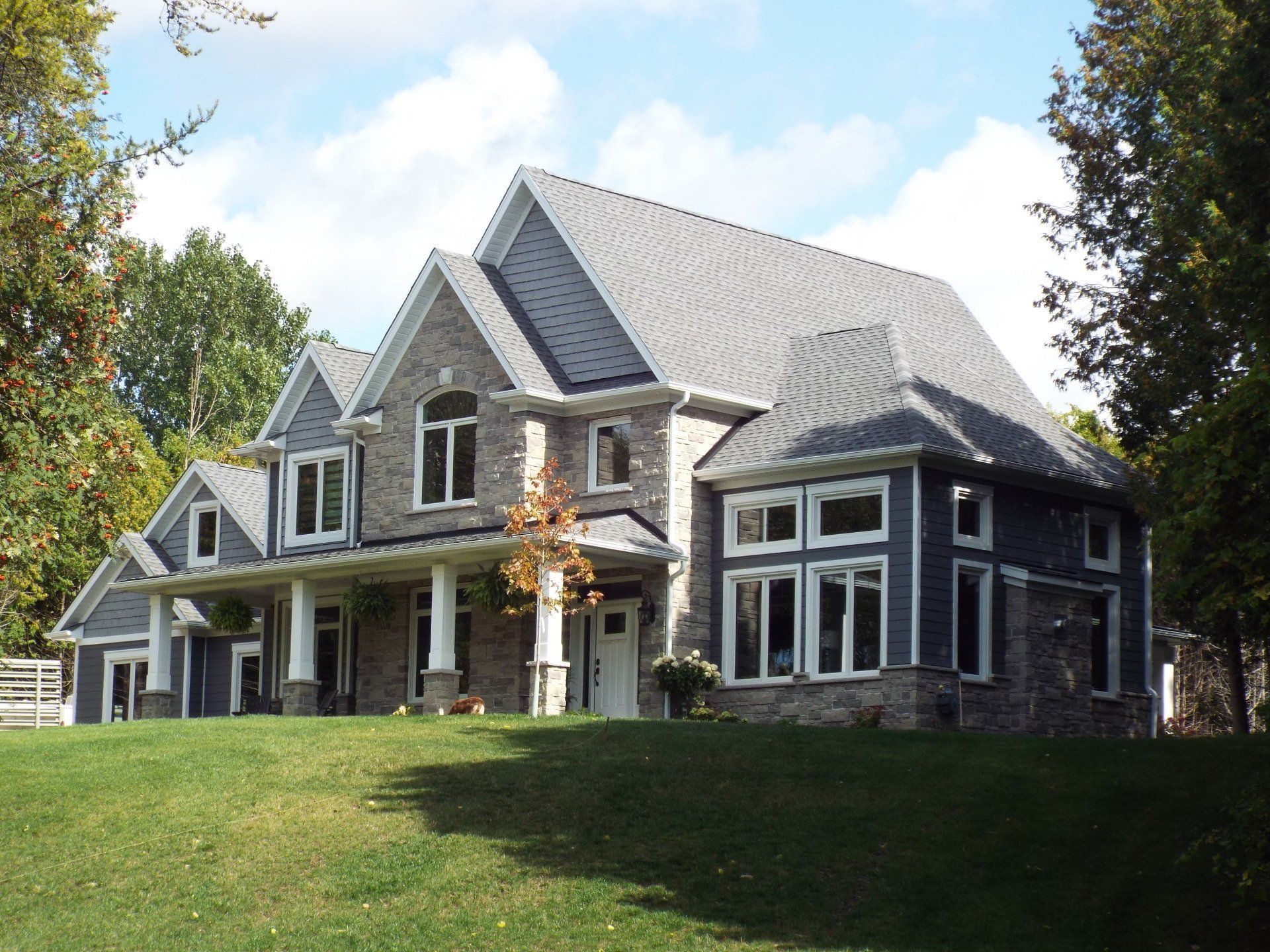 A large house sits on top of a lush green hillside