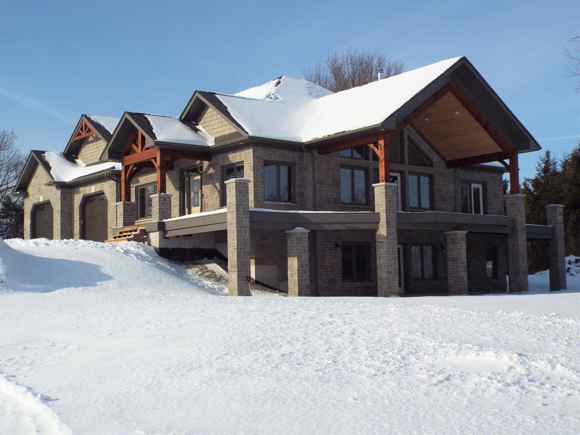 A large house is covered in snow on a sunny day