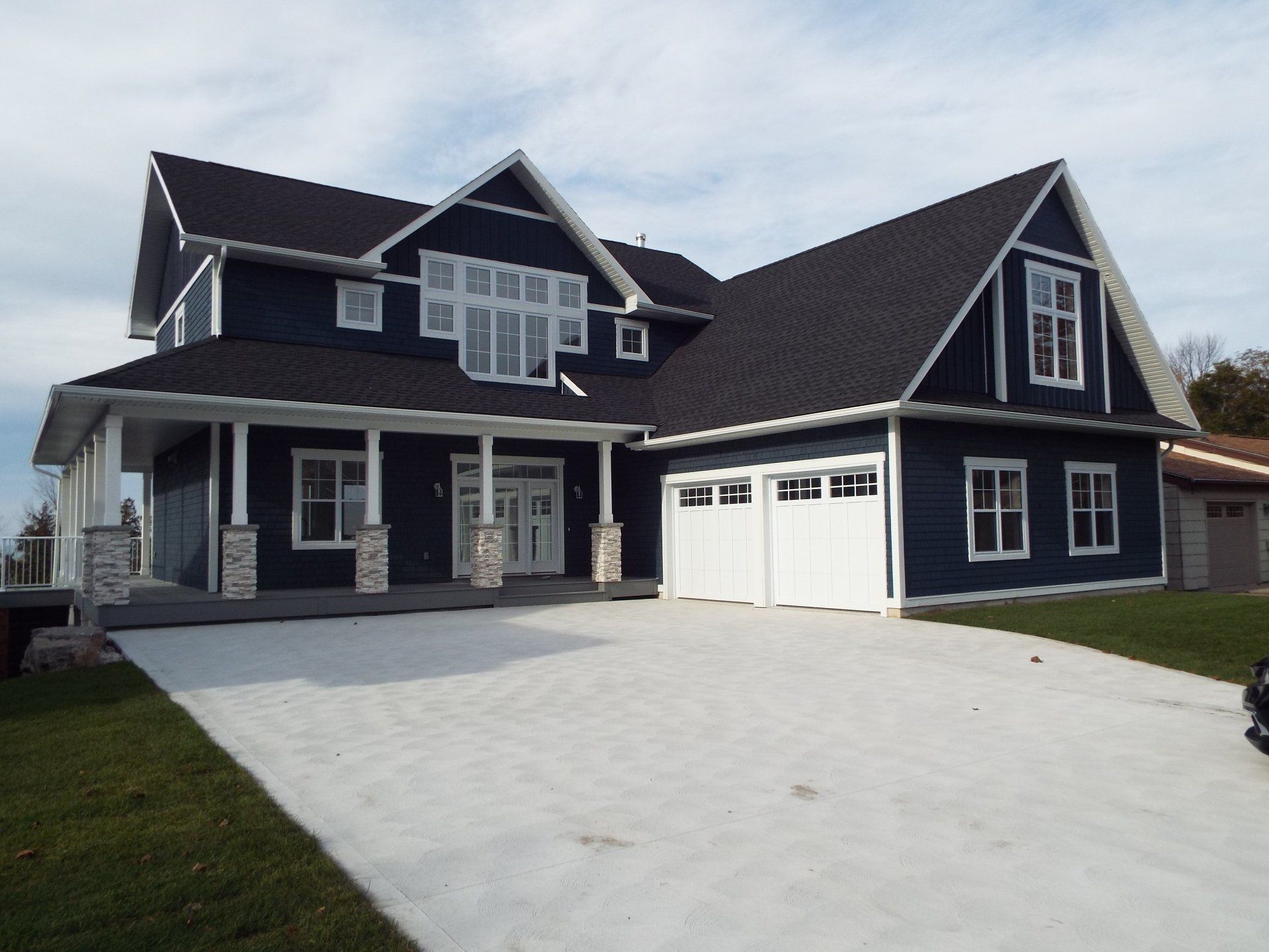 A large blue house with a black roof and white garage doors