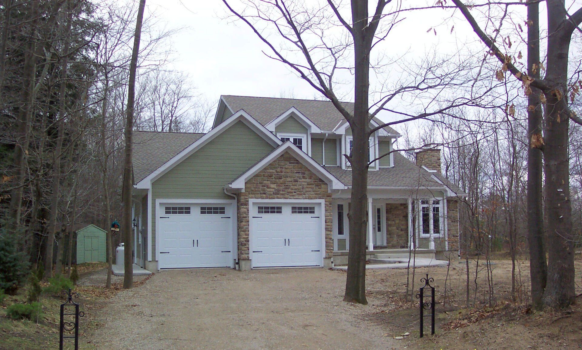 A house with two garage doors is surrounded by trees