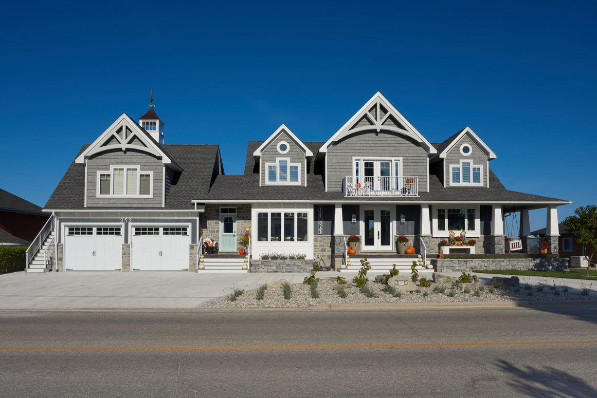 A large house with two garages is sitting on the side of the road.