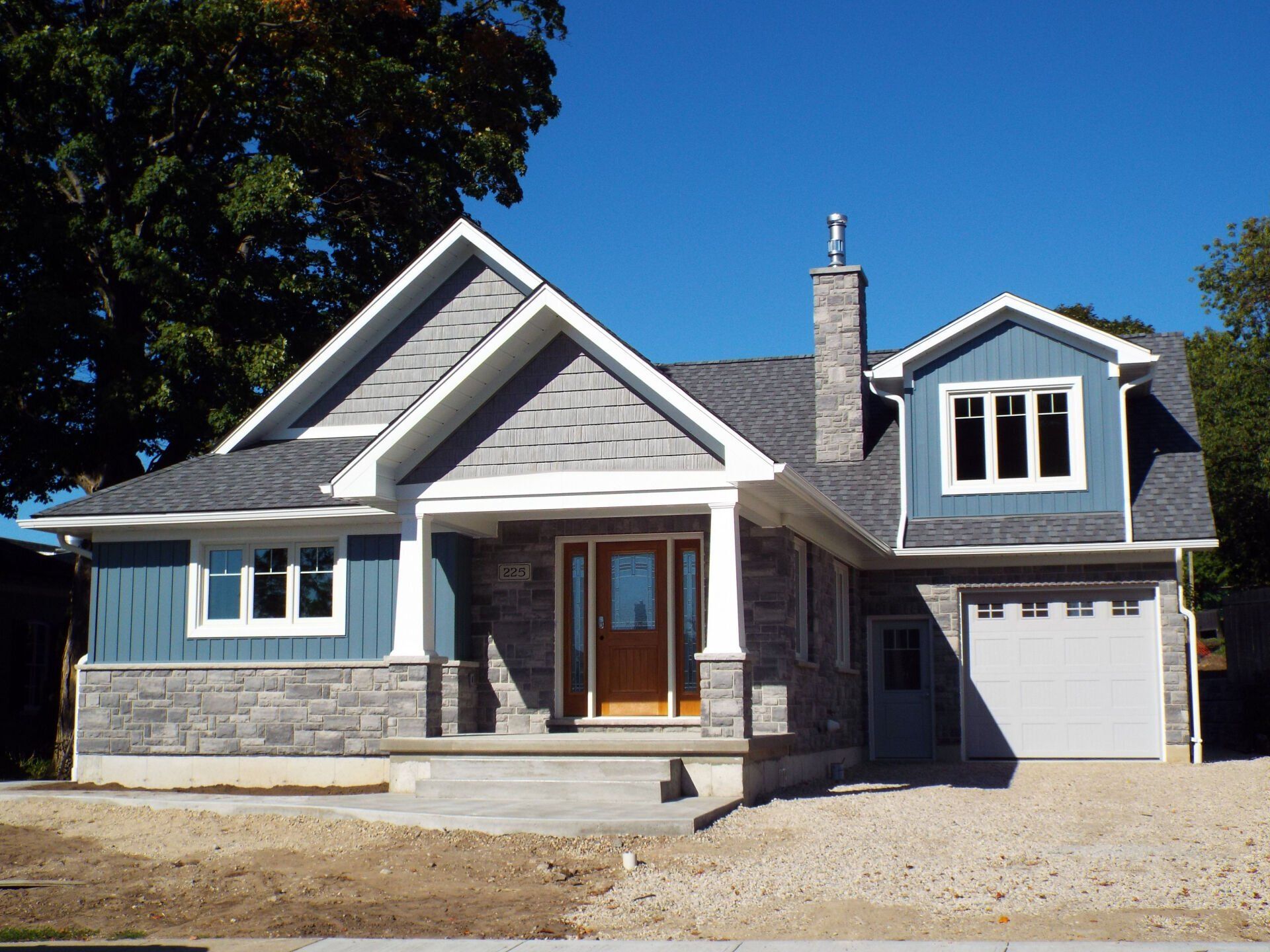 A blue and white house with a garage and a chimney