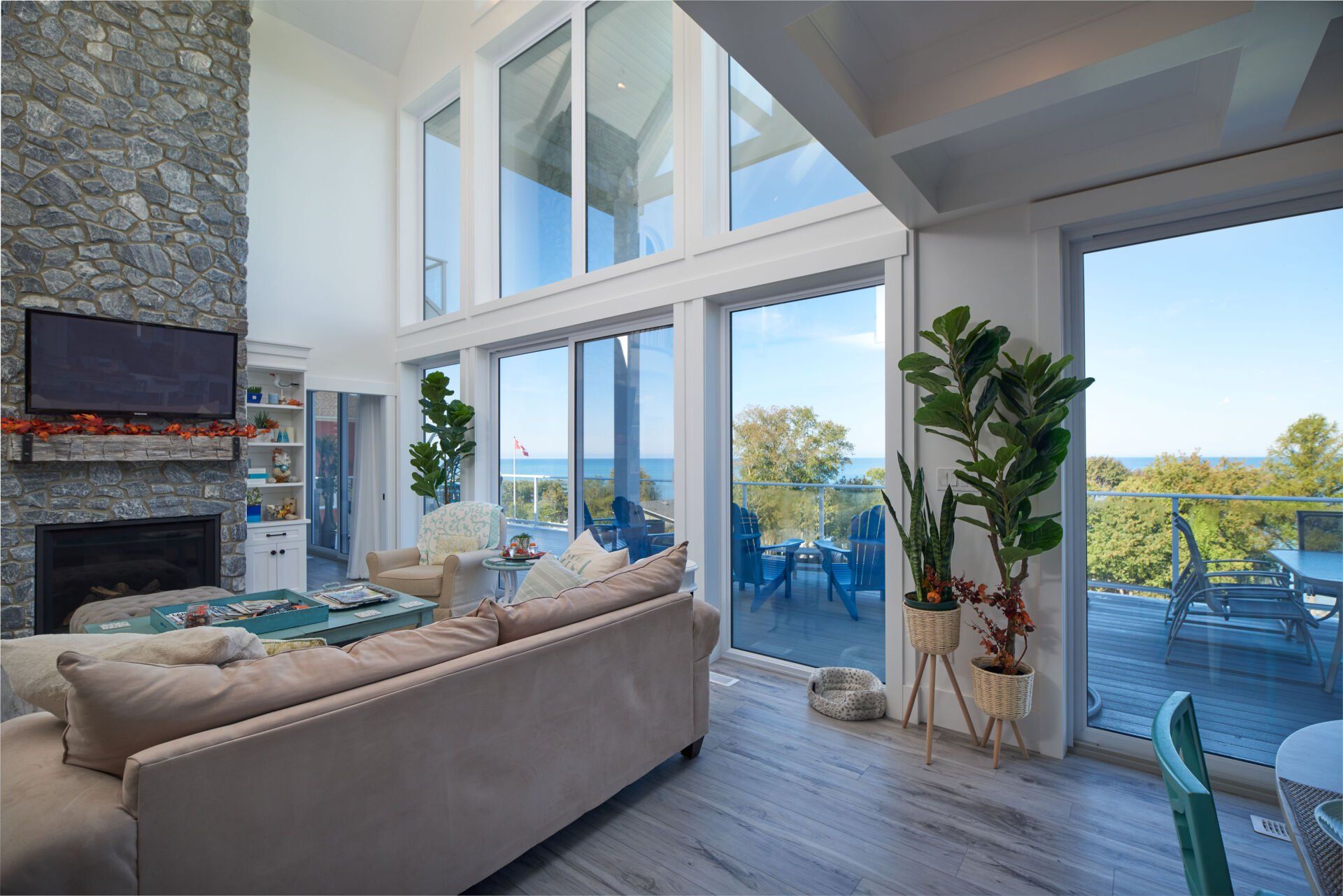 A living room with a couch , fireplace , television and lots of windows.