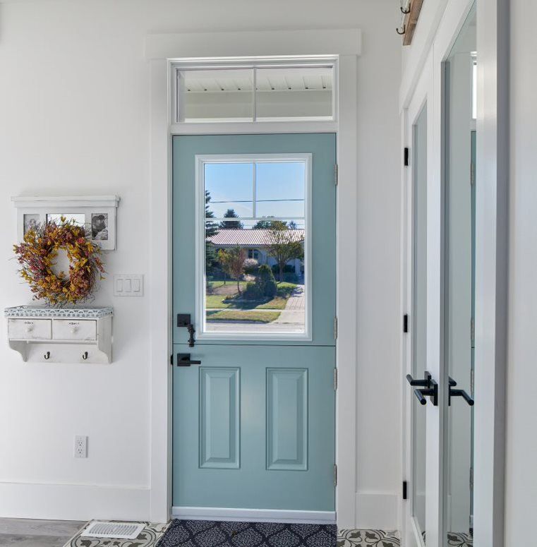 A blue door with a window and a wreath on the wall in a hallway.