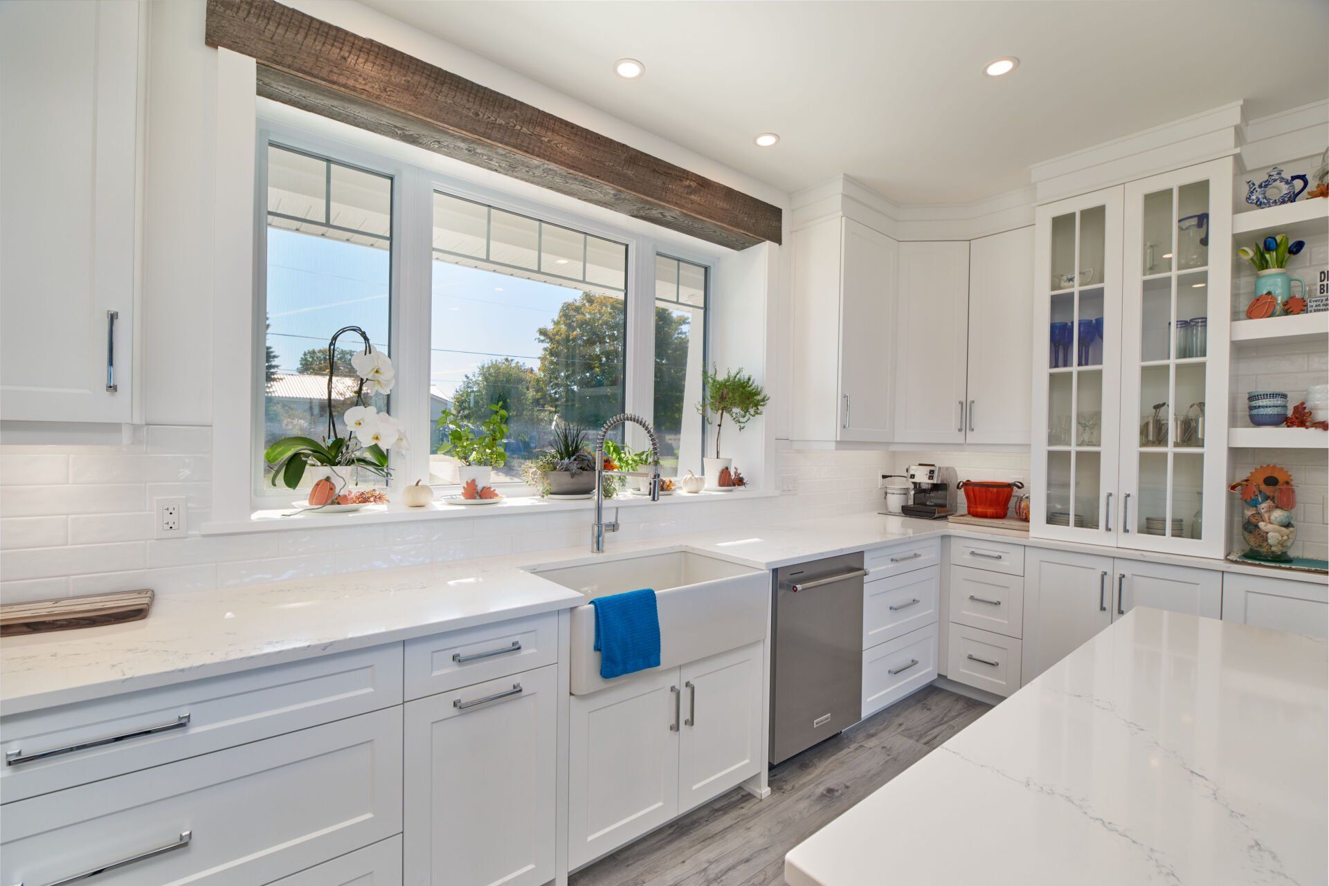A kitchen with white cabinets , stainless steel appliances , a sink , and a large window.
