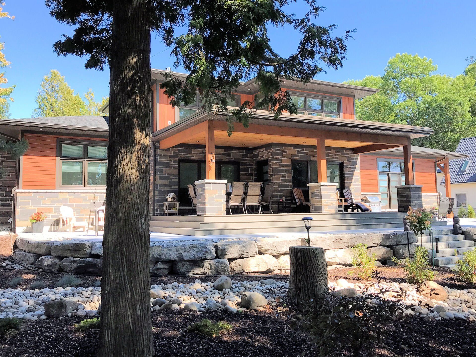 A large house with a large porch and a tree in front of it.