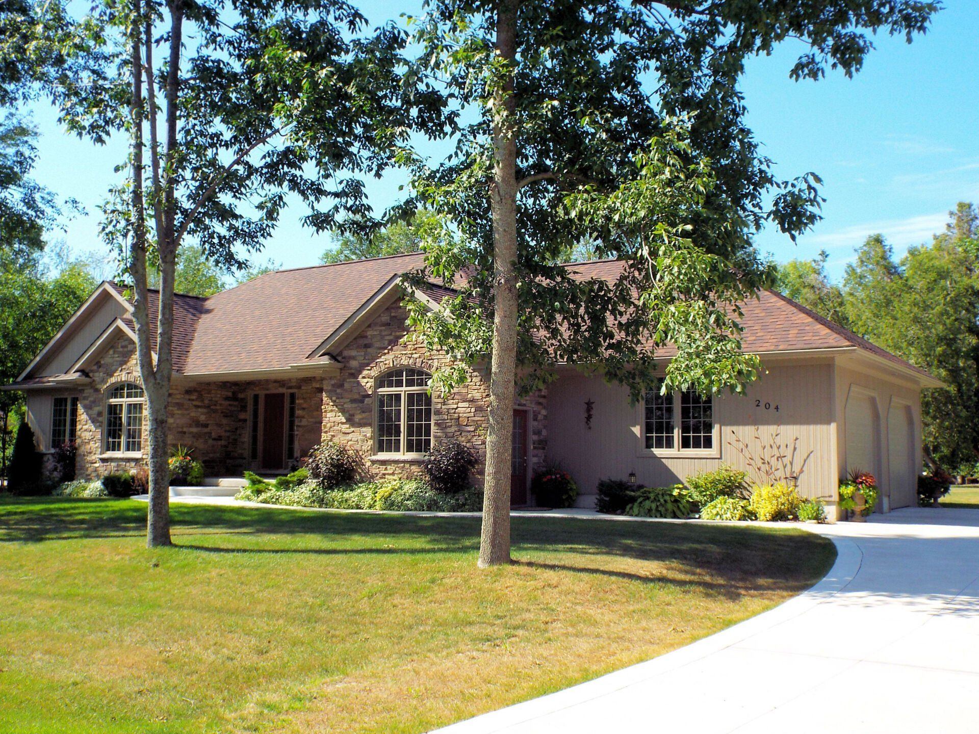 A house with a driveway and trees in front of it
