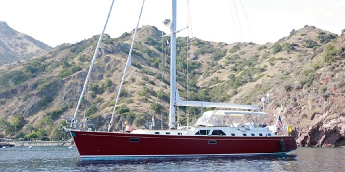 A red sailboat is floating on top of a body of water.