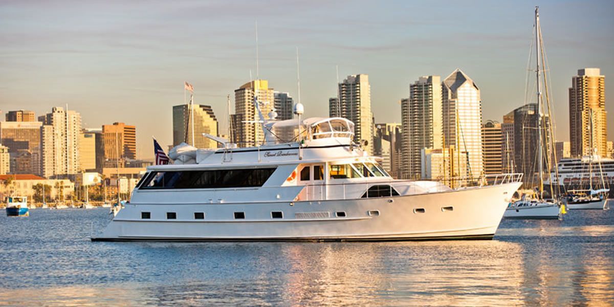 A large white yacht is floating on top of a body of water in front of a city skyline.