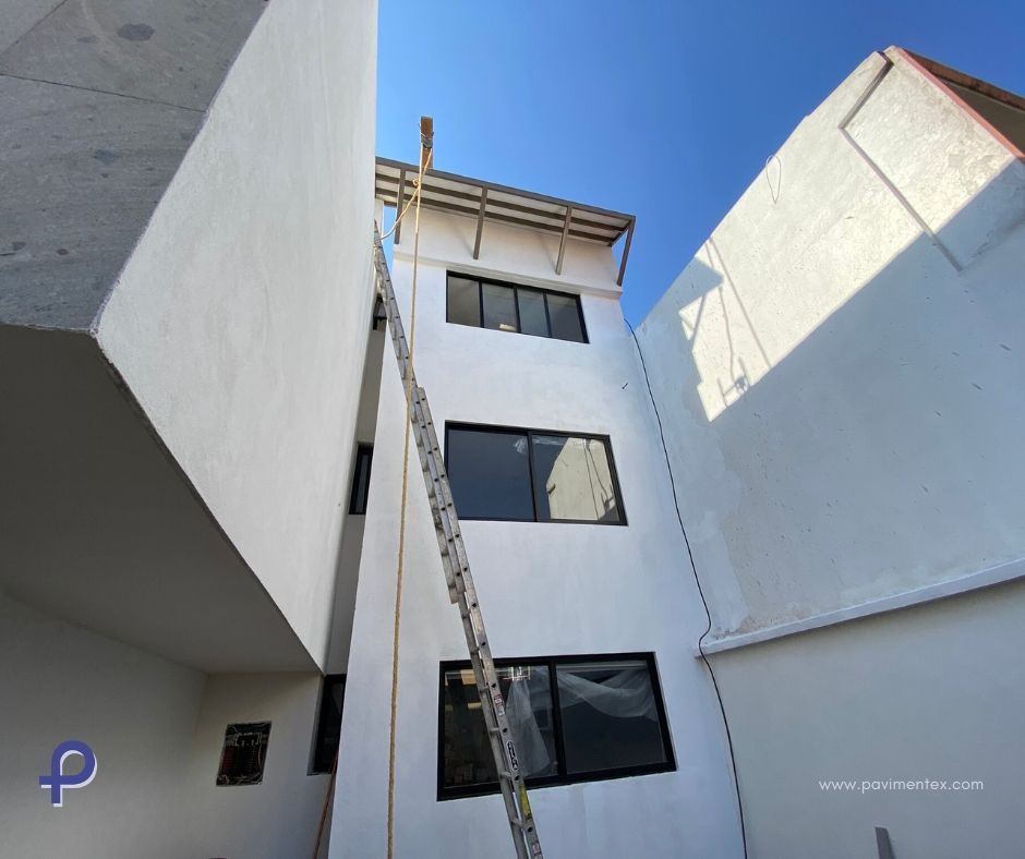 Un edificio blanco con una escalera y ventanas negras contra un cielo azul.