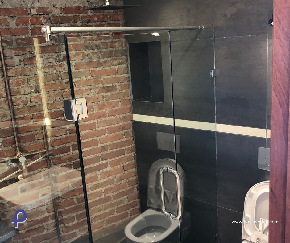 Un baño con inodoro y pared de ladrillo.