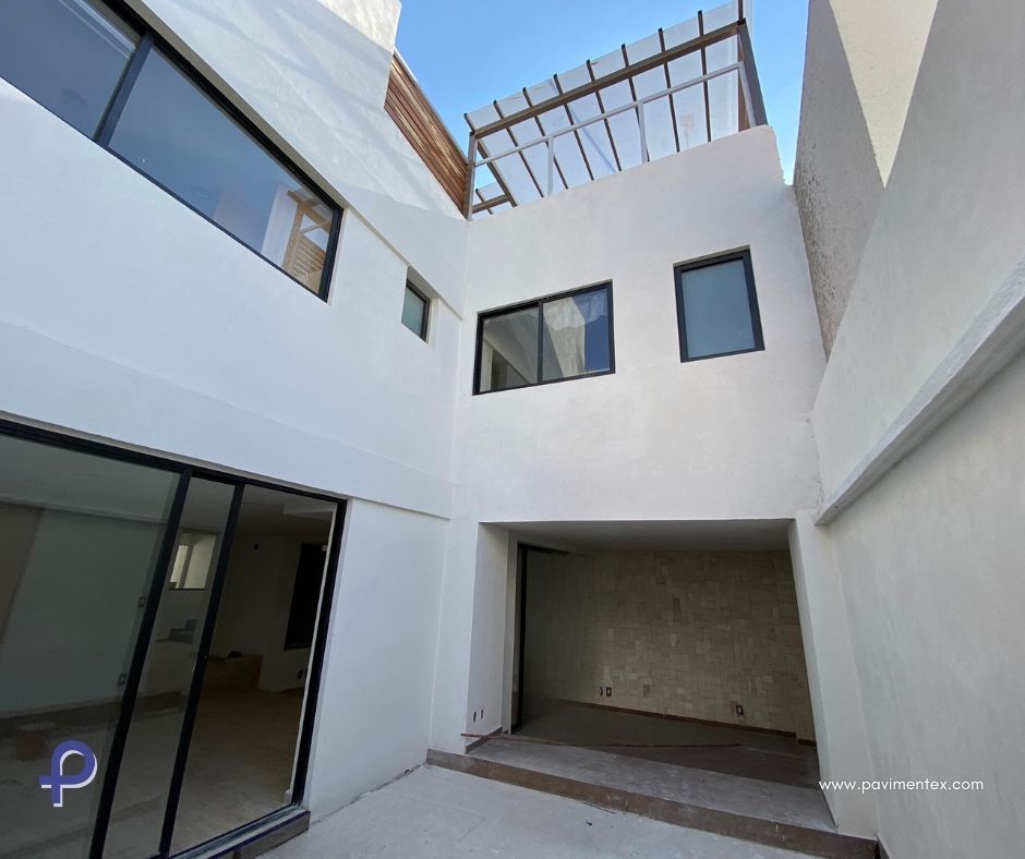 Vista exterior de un moderno edificio blanco con garaje y grandes ventanales.