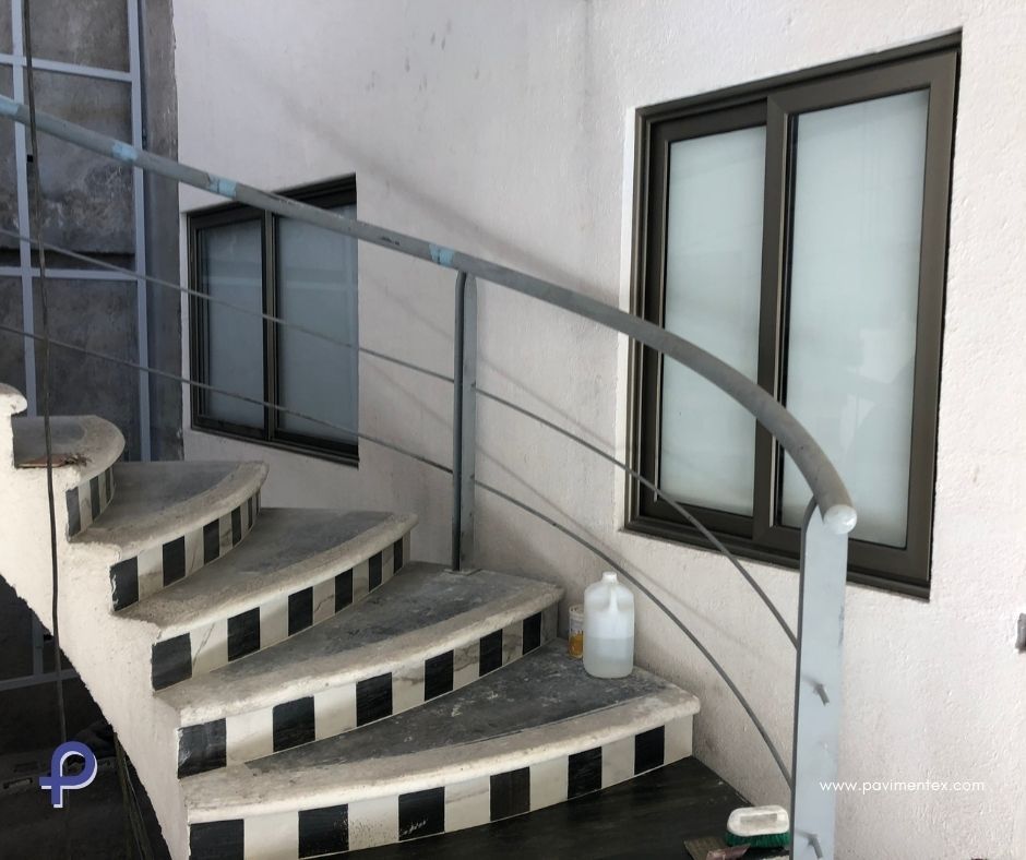 Una escalera de caracol con barandilla de metal y ventana.