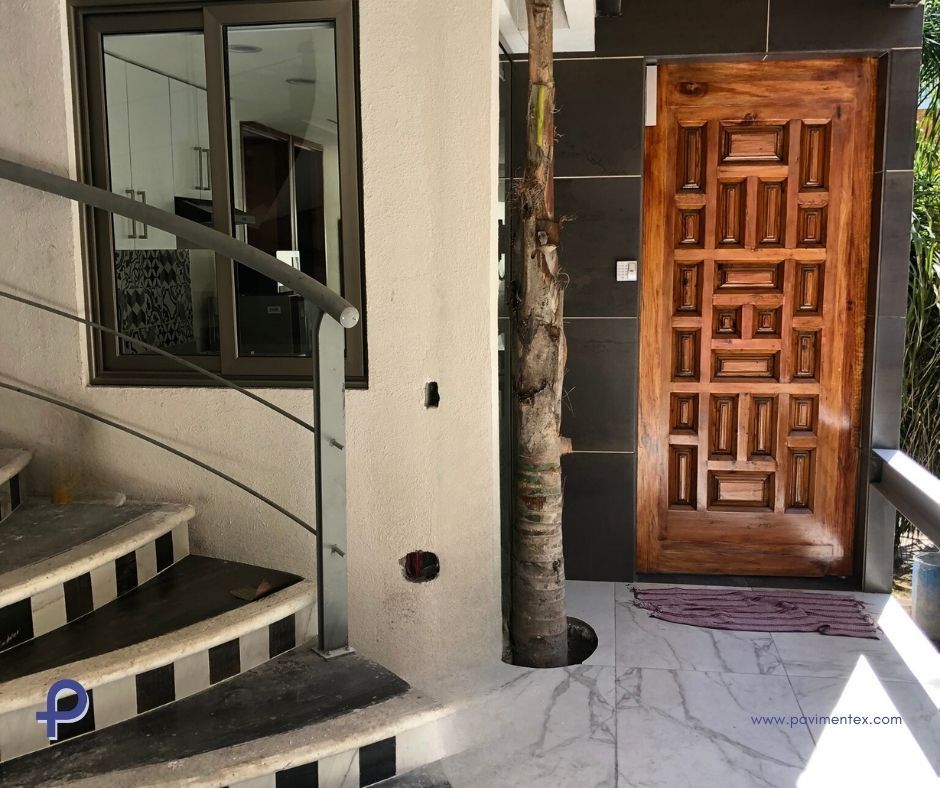 Una puerta de madera con cuadrados está al lado de unas escaleras.