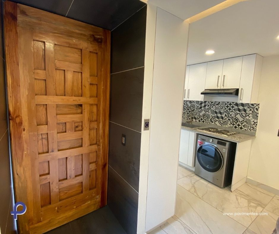 Una cocina con puerta de madera y lavadora.