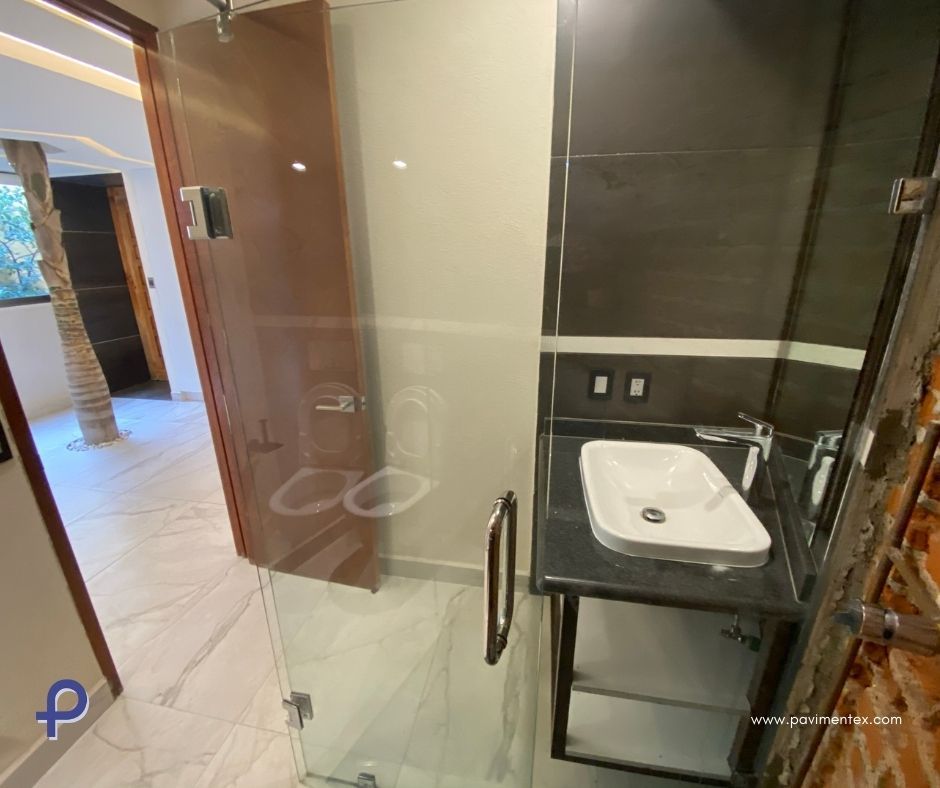 Un baño con lavabo, ducha y puerta de cristal.