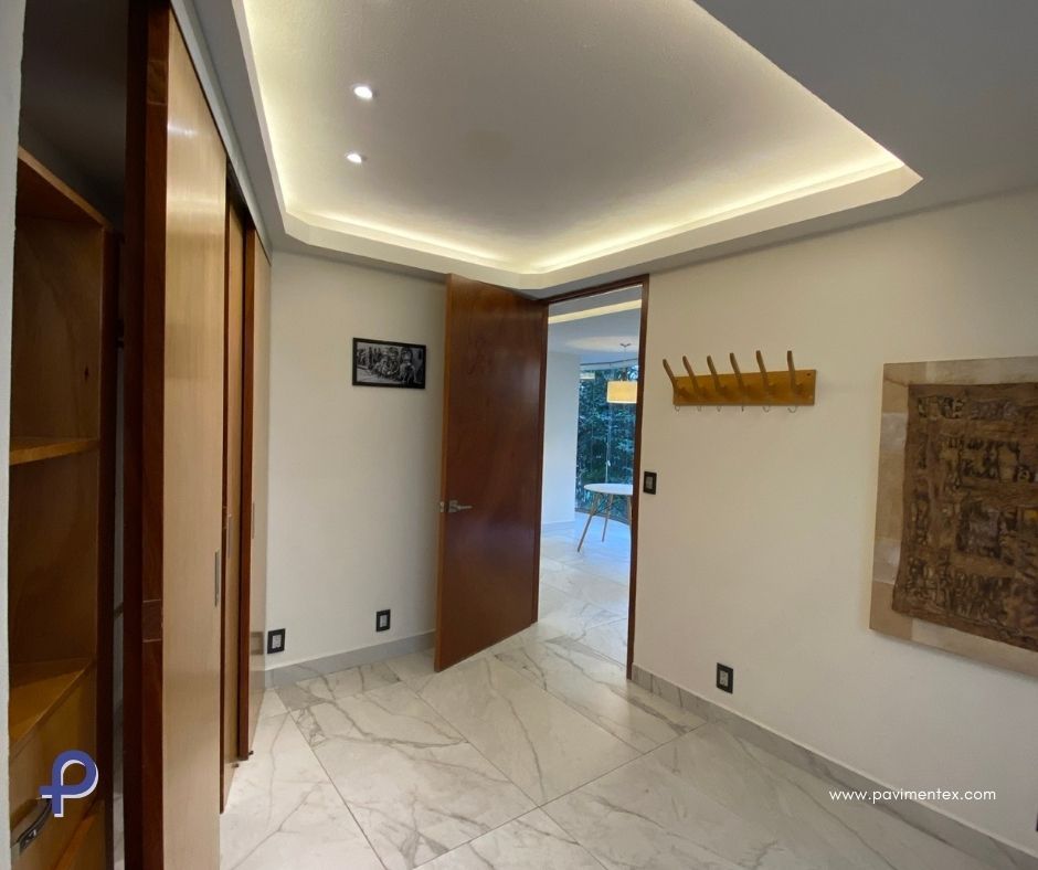 Un pasillo con puerta de madera y lámpara de techo.