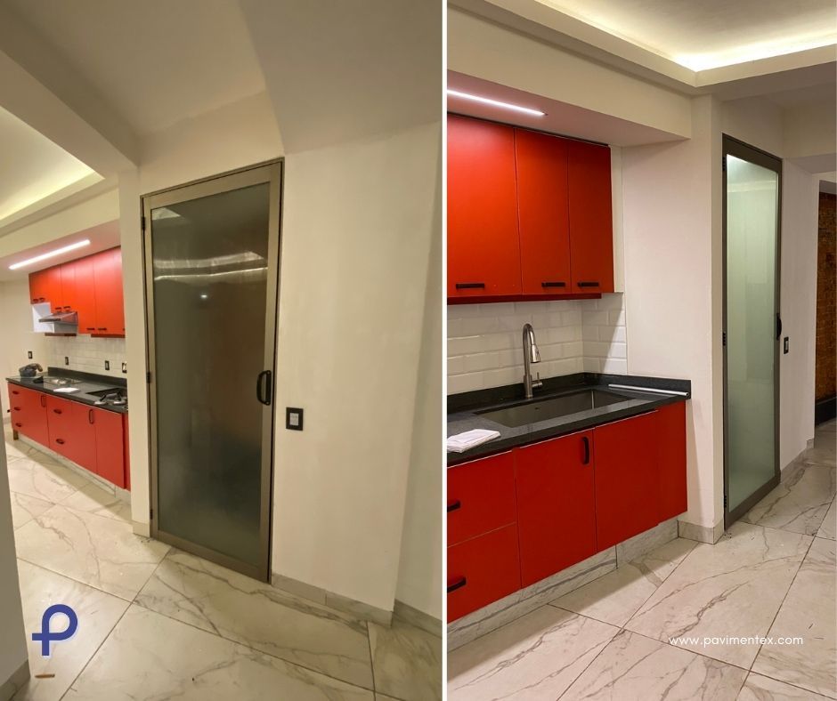 Una cocina con gabinetes rojos y puerta de vidrio.
