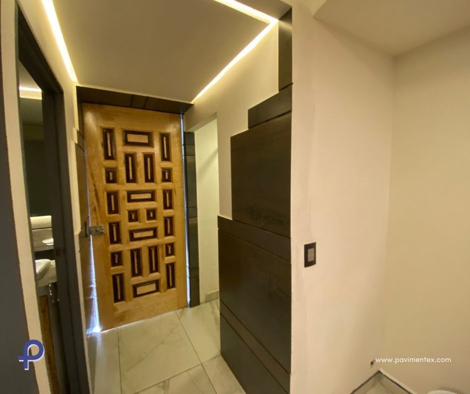 Un pasillo con una puerta de madera que conduce a un baño.