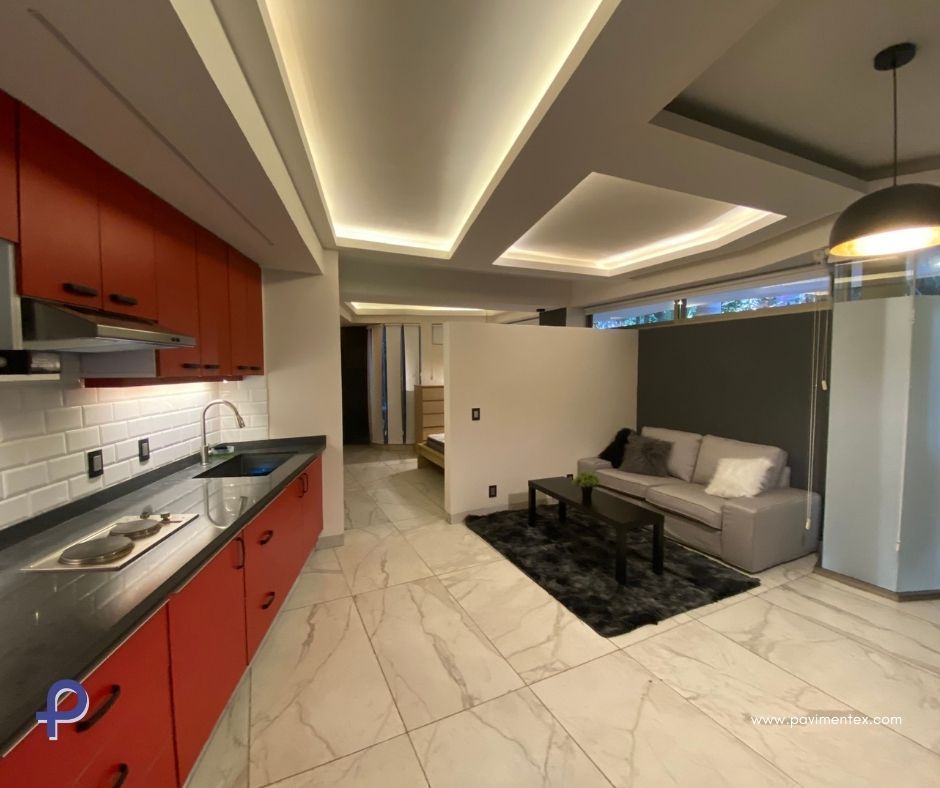 Una cocina con gabinetes rojos y una sala de estar con sofá.