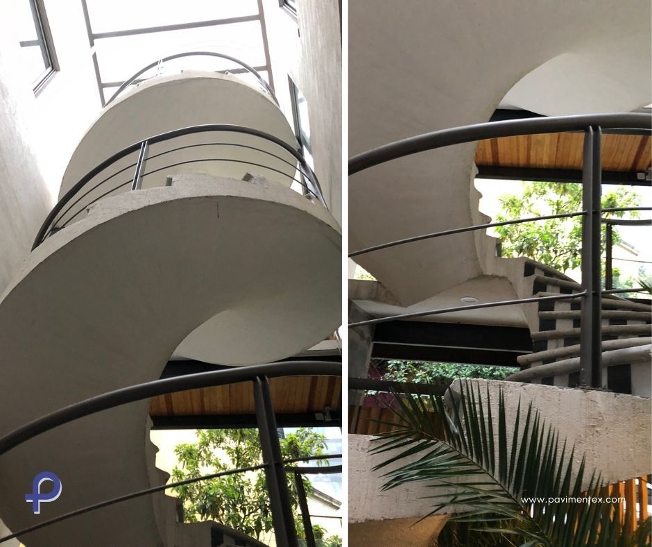 Una escalera de caracol con barandilla metálica y una palmera al fondo.