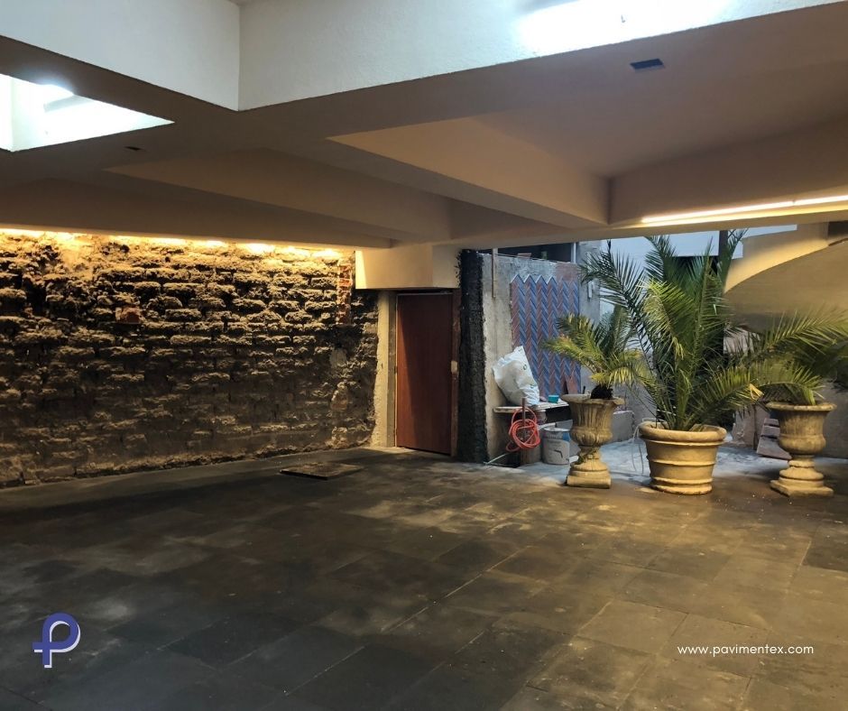 Una gran habitación vacía con una pared de ladrillo y plantas en macetas.