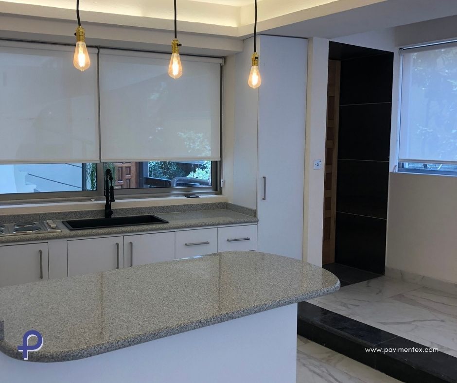 Una cocina con gabinetes blancos, encimeras de granito y fregadero.