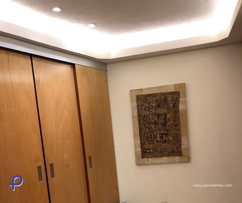 Una habitación con armarios de madera y un cuadro en la pared.