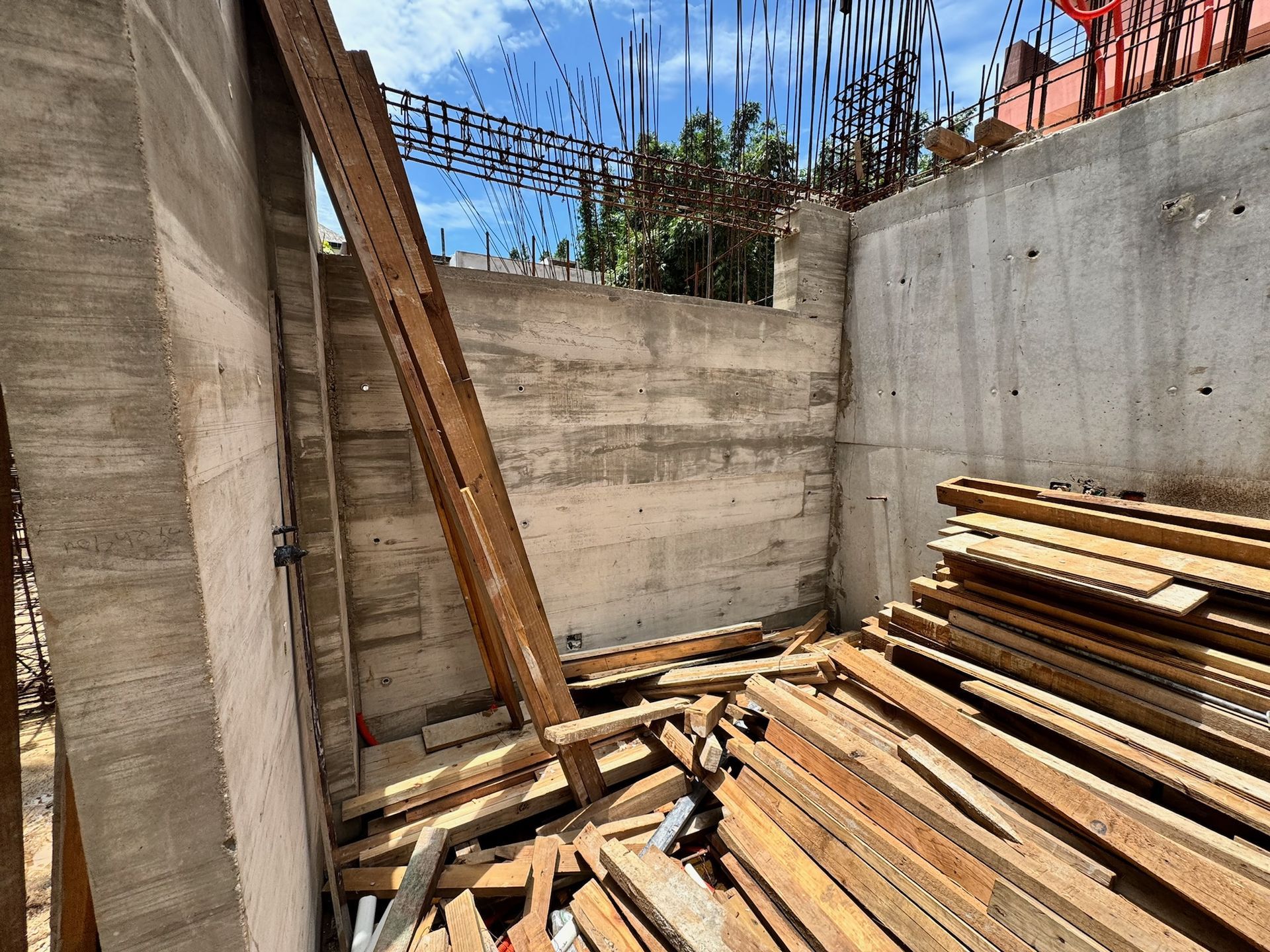 Sitio de construcción con paredes de hormigón, vigas de madera y restos de madera.