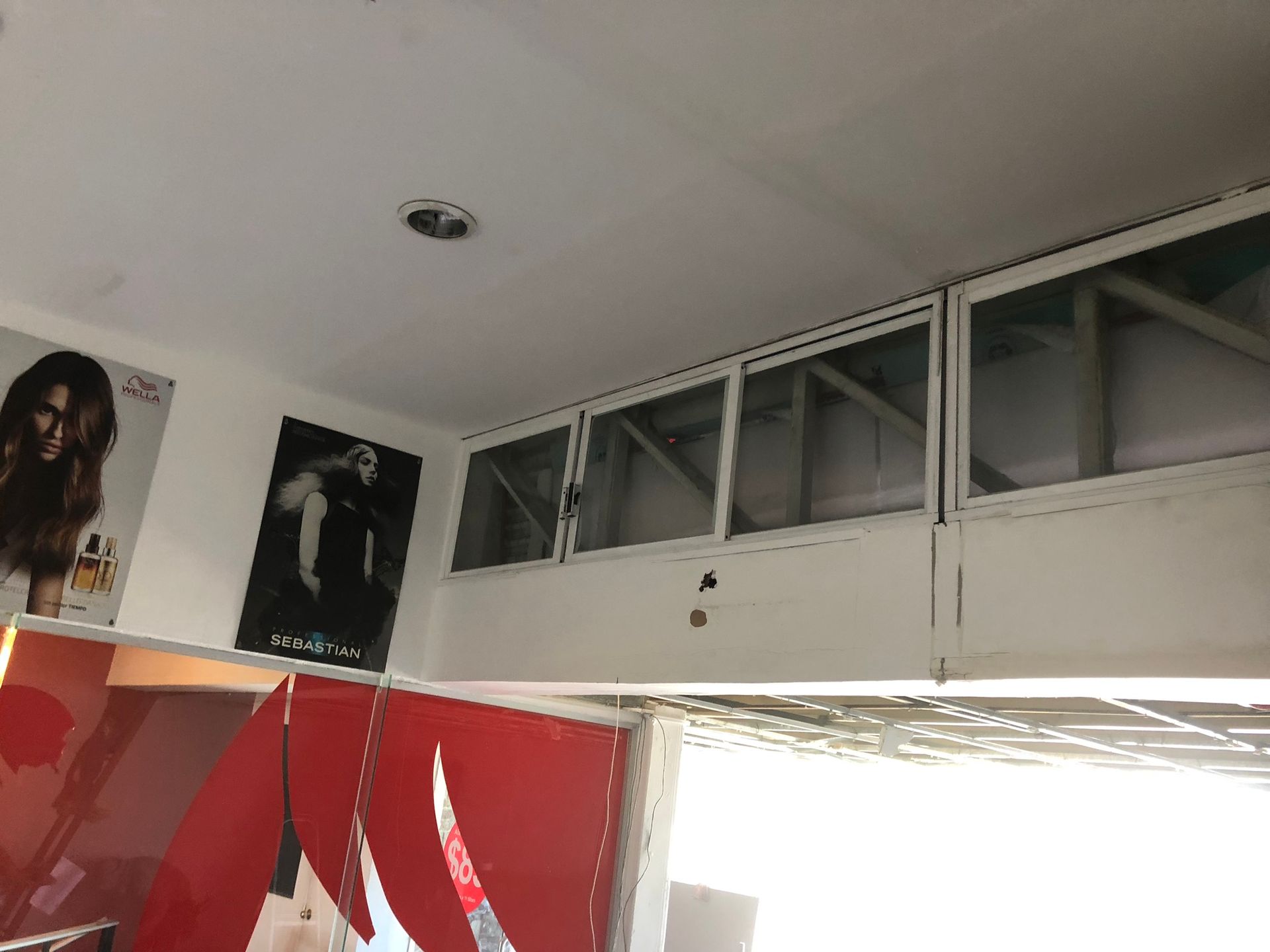 Interior de salón con carteles, detalles en rojo y pequeñas ventanas.