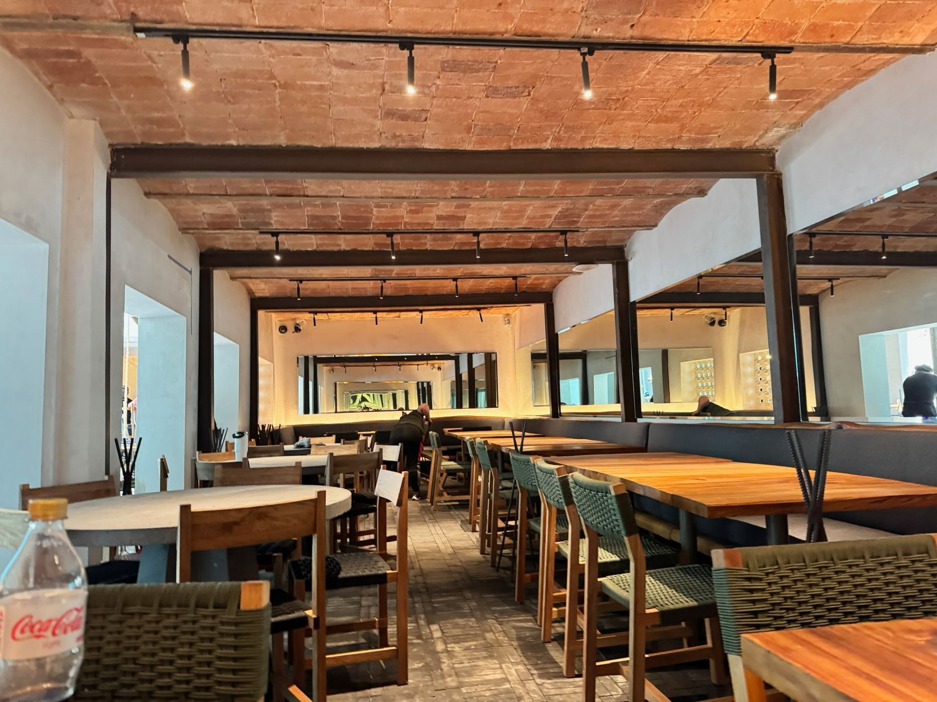 Interior de restaurante con techo de ladrillo, mesas y sillas de madera.
