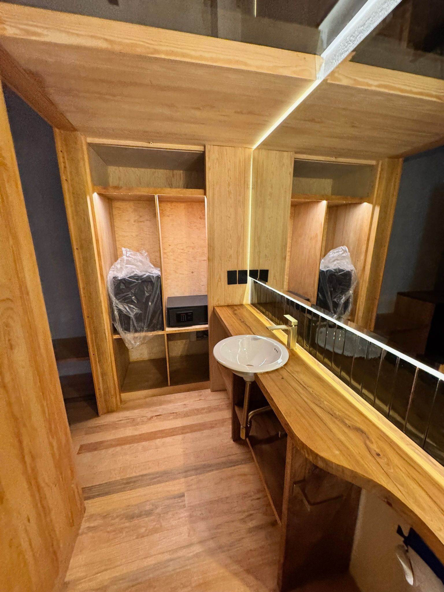 Baño de madera con lavabo, espejo y baulera.