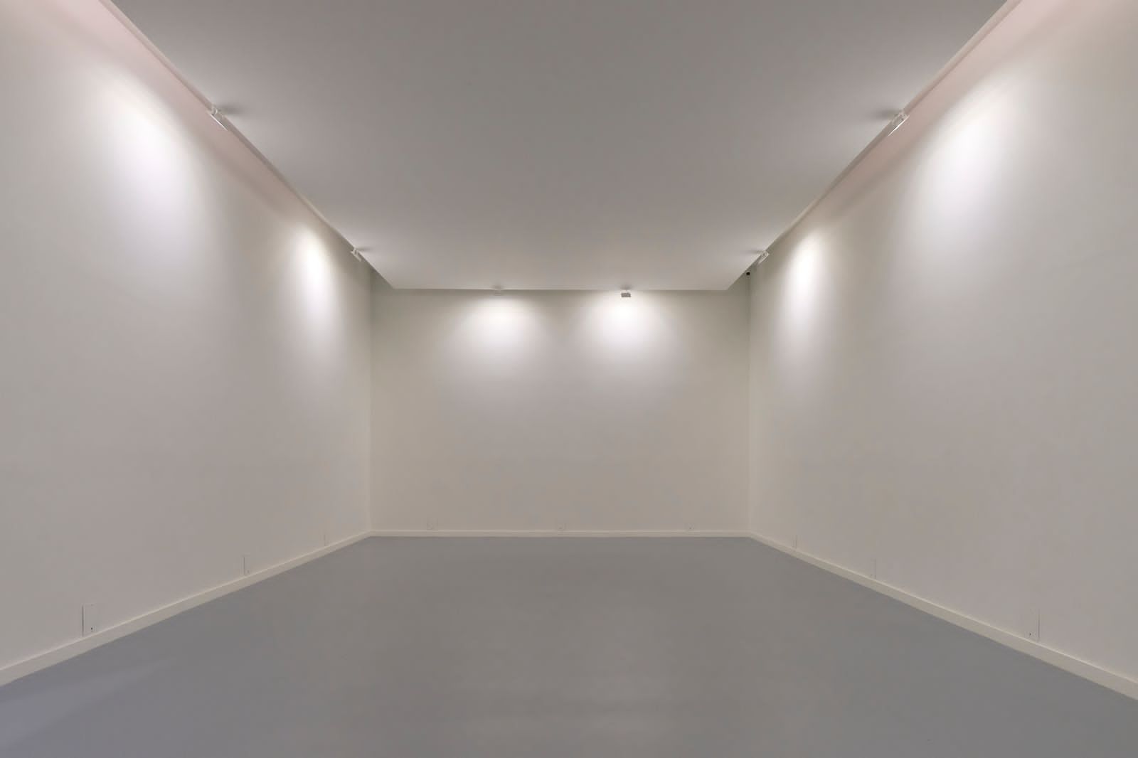 Pavimentex, construcción de una habitación vacía con paredes blancas y suelo gris.