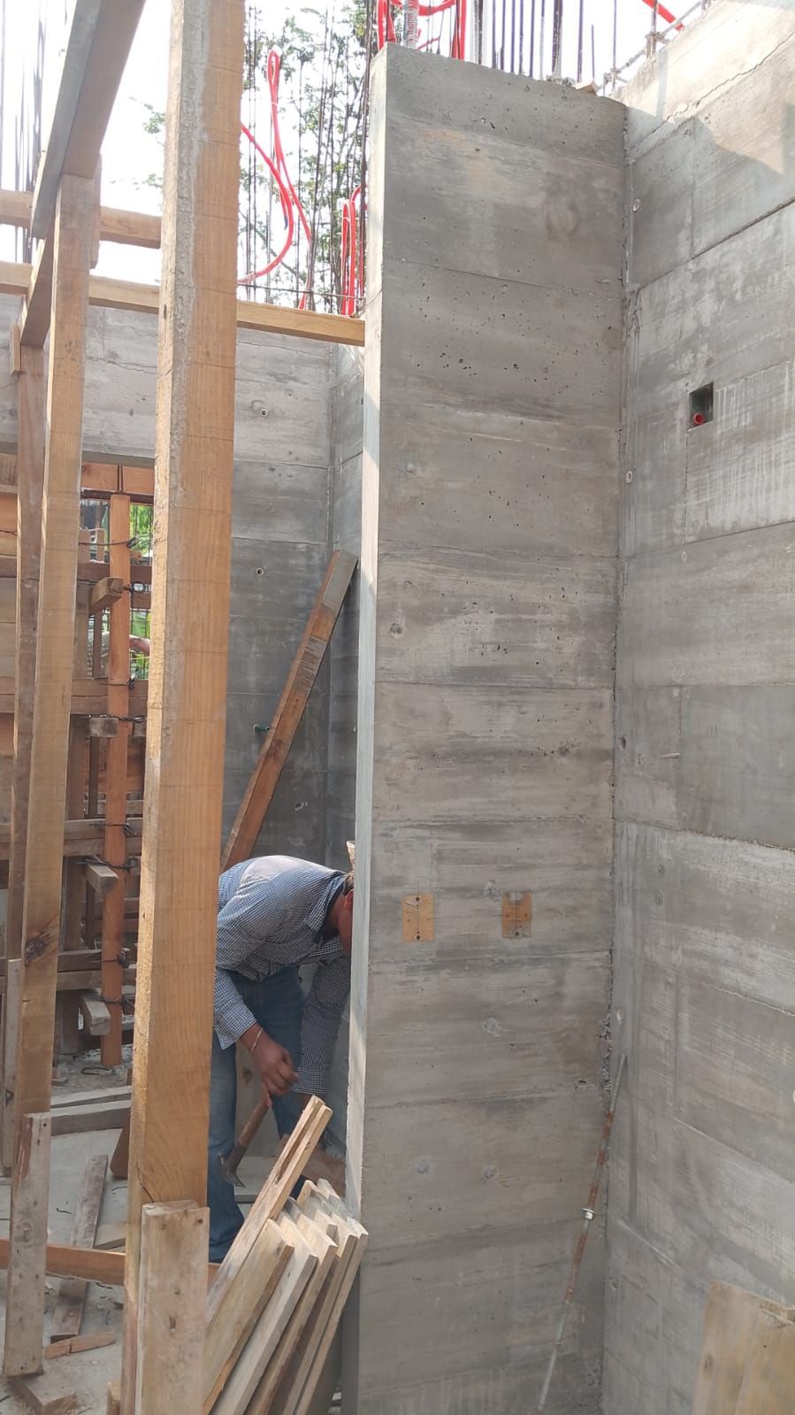 Obrero de la construcción cerca de un muro de hormigón con soportes de madera.