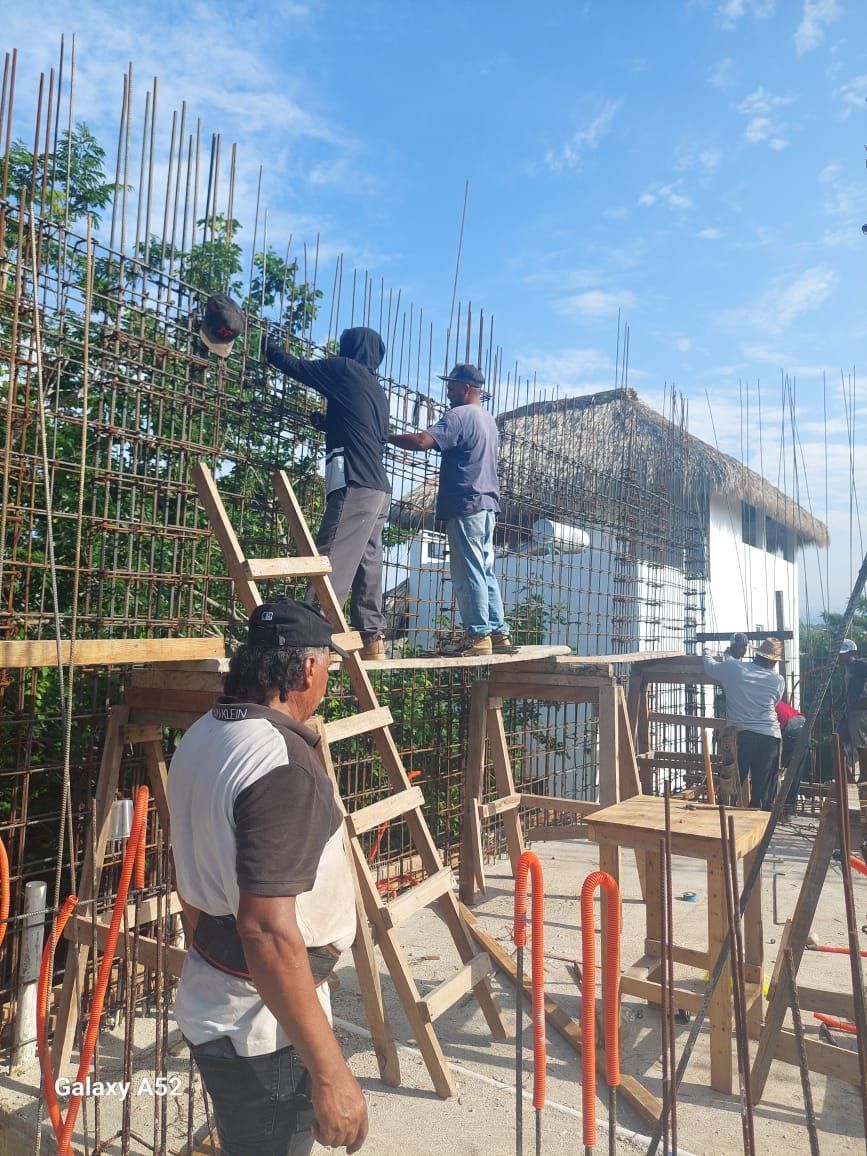 Obreros de la construcción construyendo la estructura, varillas de acero en su lugar, entorno soleado al aire libre.