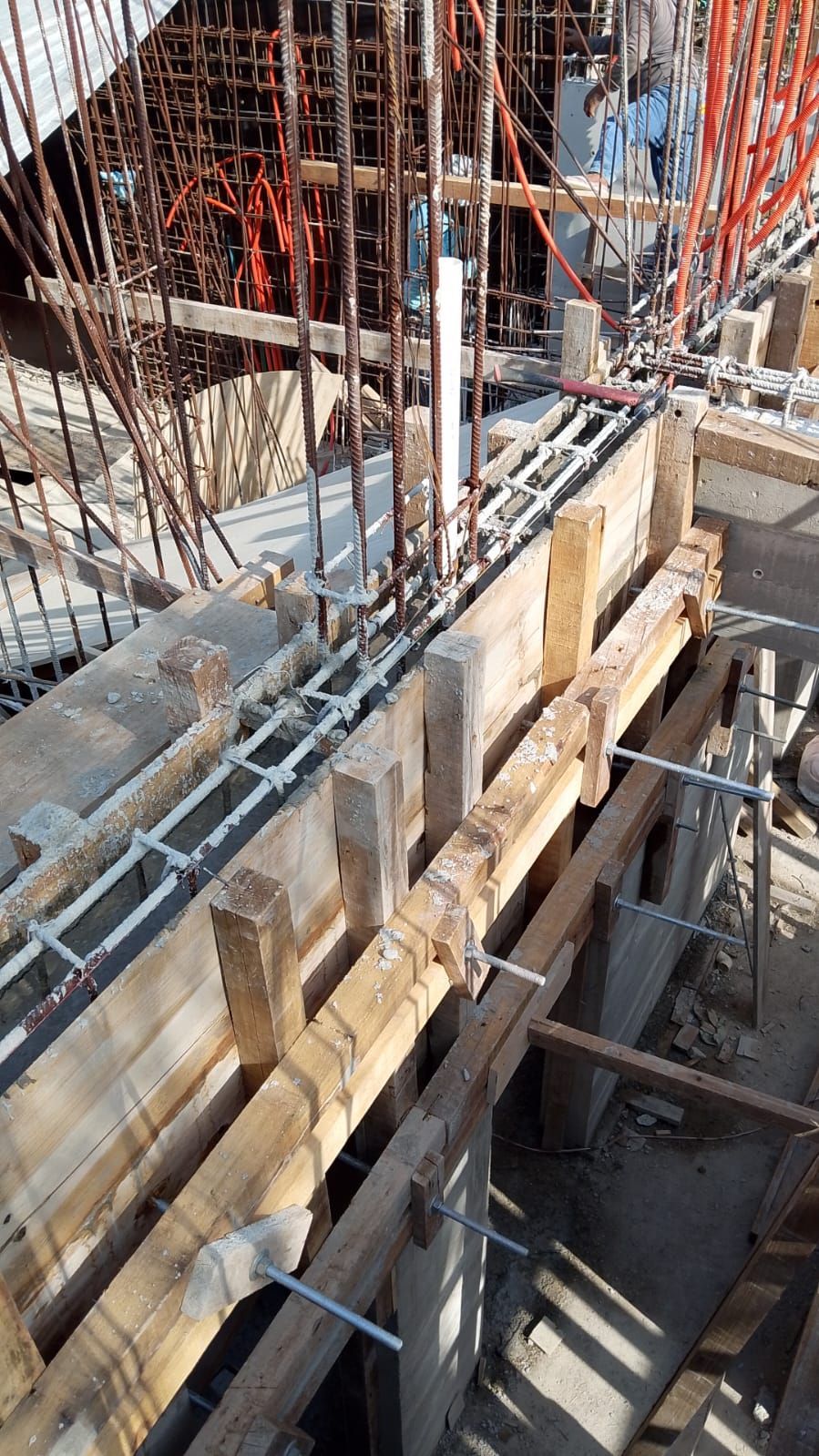 Obra de construcción con encofrado de madera, barras de acero de refuerzo y hormigón vertido.