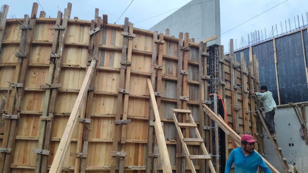 Encofrado de construcción de madera en construcción con trabajadores presentes.