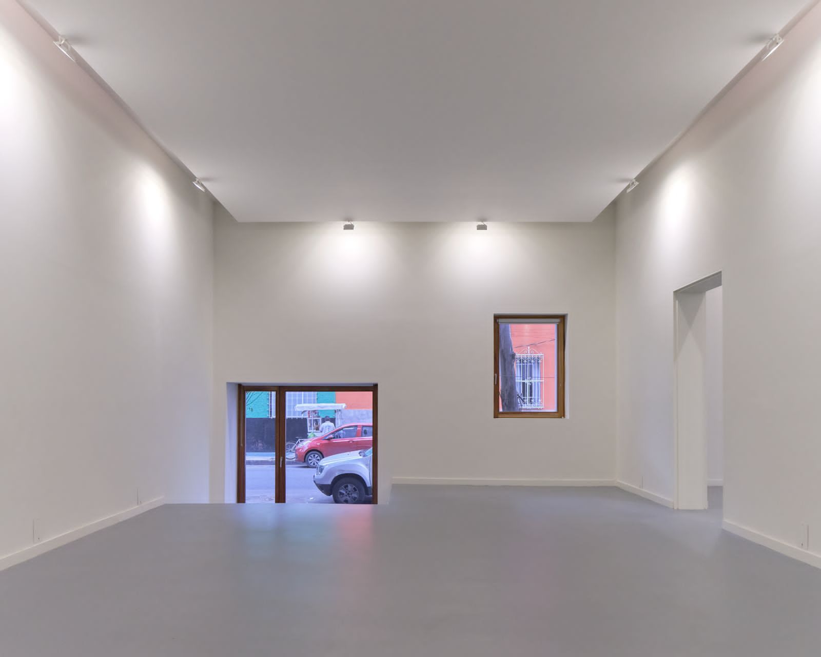 Una gran habitación vacía con un coche aparcado en la ventana.