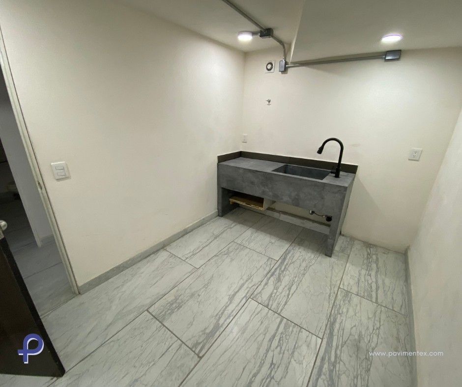 Habitación pequeña con lavabo, encimera gris y suelo de baldosas.