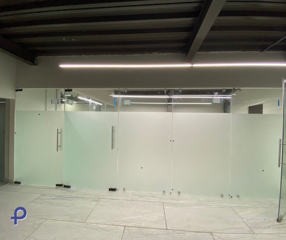 Mampara de oficina de cristal con paneles esmerilados, puertas y herrajes plateados.