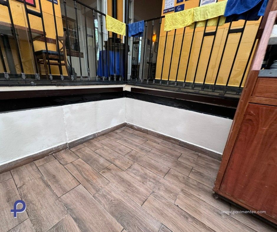 Un balcón con suelo de madera y barandilla metálica.