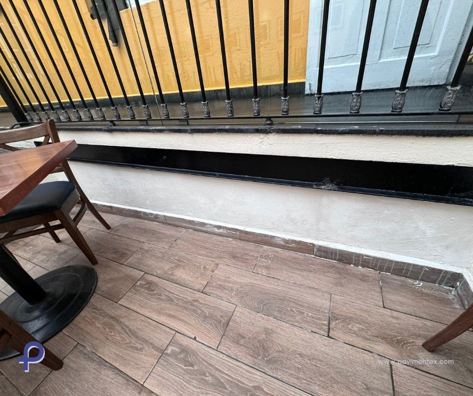 Una mesa y sillas están colocadas en un patio junto a una barandilla.