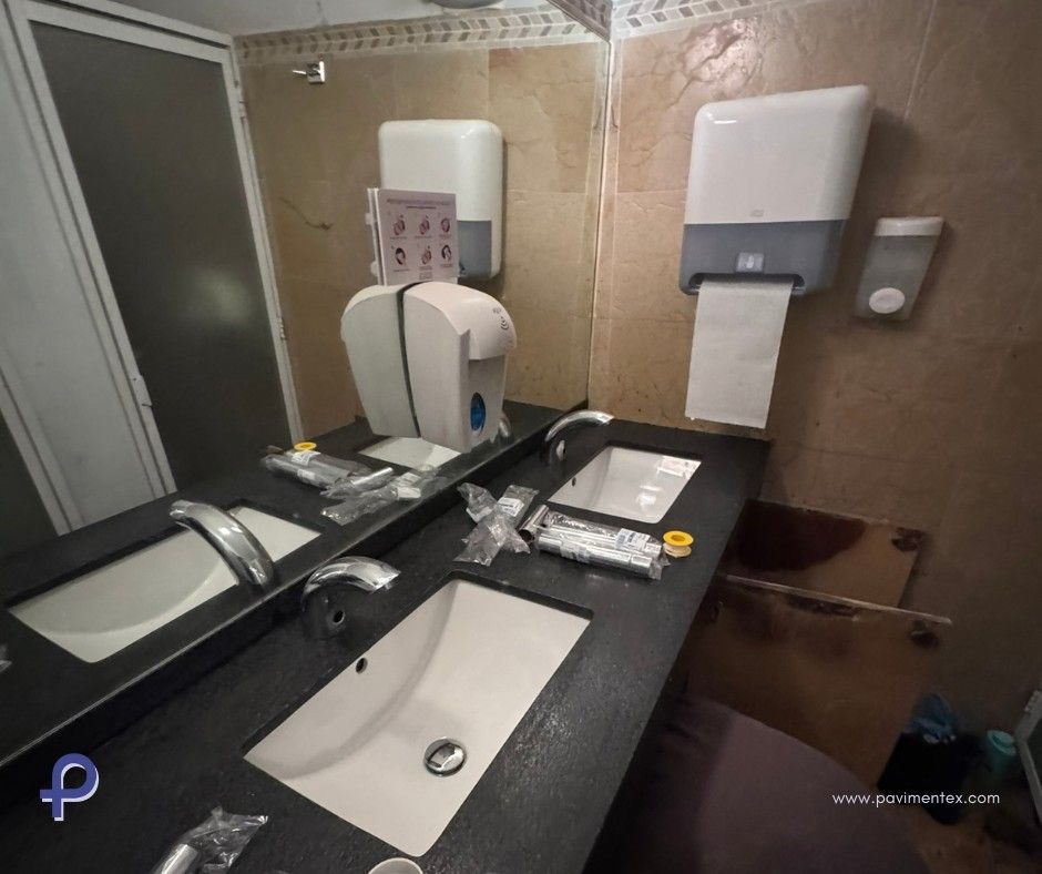 Un baño con dos lavabos y dispensador de papel higiénico.