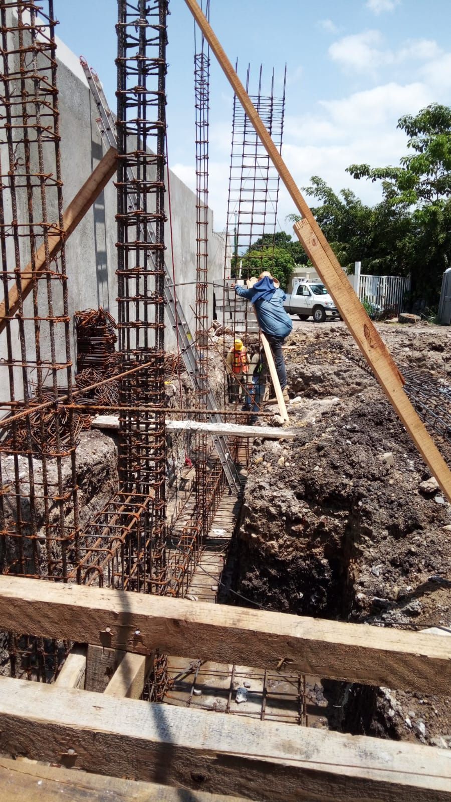 Sitio de construcción con trabajadores colocando barras de refuerzo para pilares de hormigón.