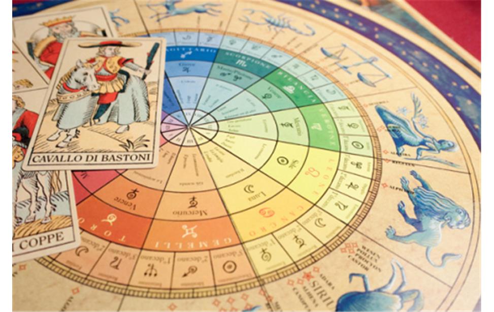 Carte dei tarocchi adagiate su un colorato grafico astrologico circolare che raffigura segni zodiacali e simboli planetari.