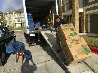 A man moving U-Haul boxes off a truck ramp into a building.