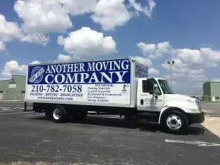 White moving truck with blue logo of “Another Moving Company” parked outdoors under a blue sky.