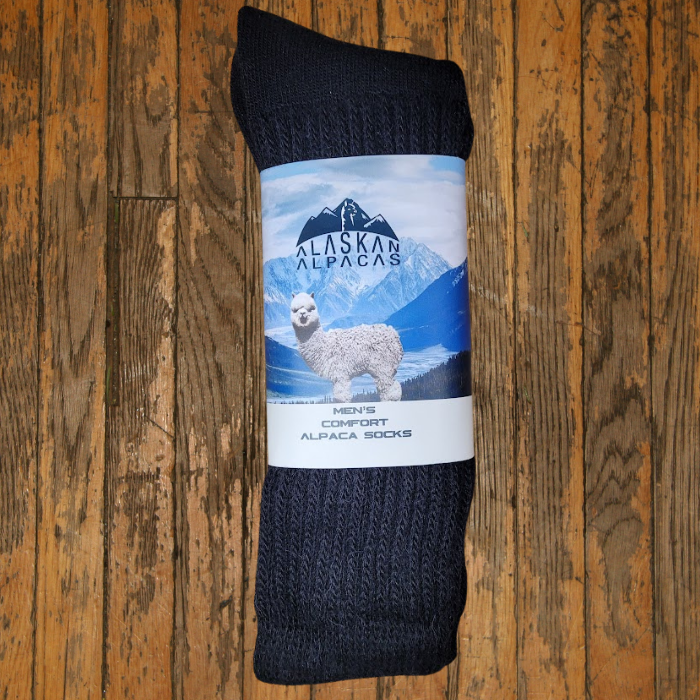 Dark gray alpaca wool socks with a white label, on a wood background.